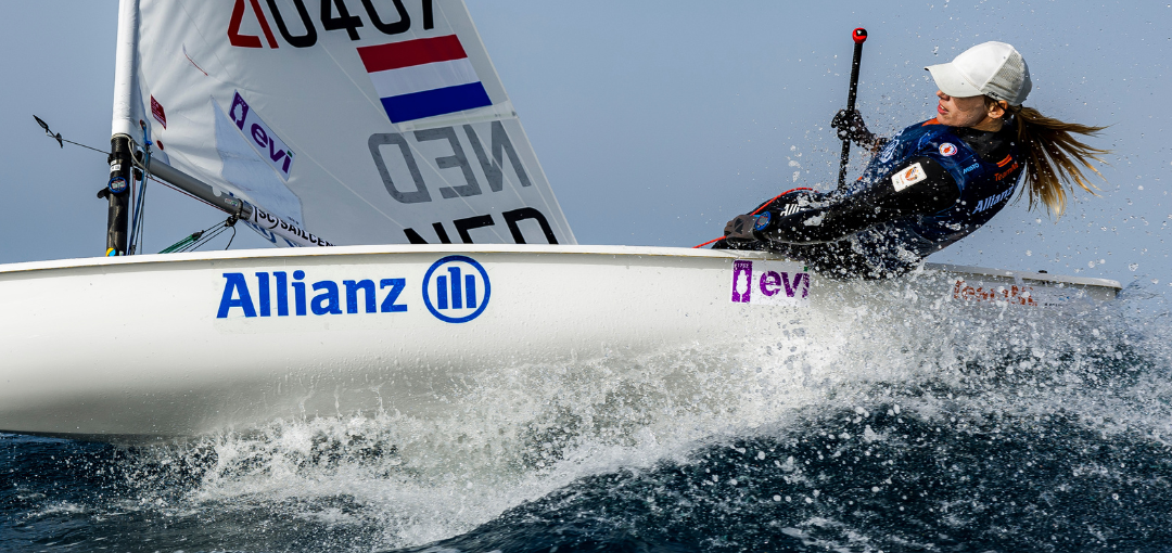 Marit Bouwmeester in haar zeilboot, elegant zeilend op het water onder een stralende lucht en een serene omgeving.