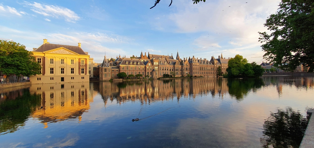 Imposant gebouw van het Binnenhof in Den Haag, met een ruime vijver aan de voorkant.